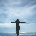 silhouette photography of woman standing on rock