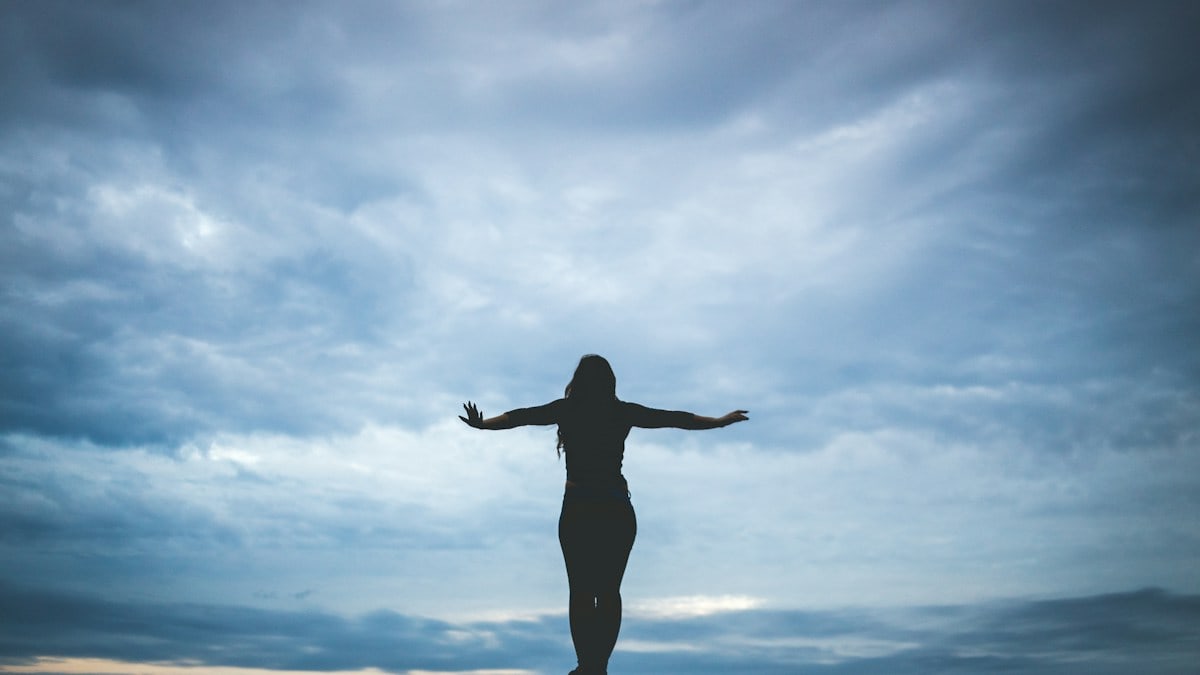 silhouette photography of woman standing on rock